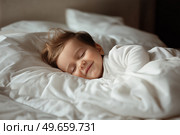 Beautiful smiling baby sleeping peacefully on cozy white bedding. Красивый улыбающийся ребенок мирно спит на уютном белом постельном белье. Стоковое AI-изображение, AI-художник Katsiaryna Repich / Фотобанк Лори