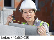 young woman is measuring a wall with measuring tape. Стоковое фото, агентство Ingram Publishing / Фотобанк Лори