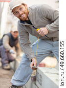 tradesman holding a plumb line beside concrete blocks. Стоковое фото, агентство Ingram Publishing / Фотобанк Лори