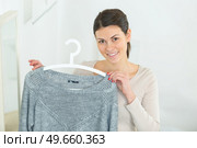 smiling hesitant young woman holding a shirt. Стоковое фото, агентство Ingram Publishing / Фотобанк Лори