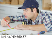 young man measuring home furniture with measure tape. Стоковое фото, агентство Ingram Publishing / Фотобанк Лори