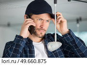 a man talking on the phone while fixing a light. Стоковое фото, агентство Ingram Publishing / Фотобанк Лори