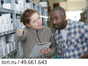 female warehouse staffadvising colleague by pointing forwards. Стоковое фото, агентство Ingram Publishing / Фотобанк Лори