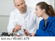 female apprentice repairing electrical appliance under supervision. Стоковое фото, агентство Ingram Publishing / Фотобанк Лори