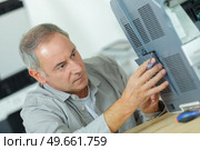 senior technician fitting grill on electrical appliance. Стоковое фото, агентство Ingram Publishing / Фотобанк Лори