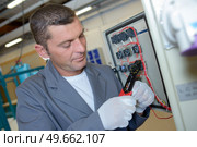 an electrician using cable strippers. Стоковое фото, агентство Ingram Publishing / Фотобанк Лори