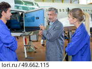 Students looking in compartment of aircraft. Стоковое фото, агентство Ingram Publishing / Фотобанк Лори