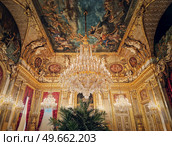 Beautiful decorated Napoleon apartments at Louvre palace. Royal family rooms with cardinal red curtains, golden ornate walls, paintings and crystal chandeliers suspended from ceiling. Стоковое фото, агентство Ingram Publishing / Фотобанк Лори