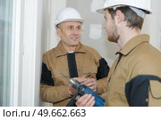 Workmen chatting, one holding electric drill. Стоковое фото, агентство Ingram Publishing / Фотобанк Лори