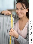woman inspecting hand luggage measurement using measuring tape. Стоковое фото, агентство Ingram Publishing / Фотобанк Лори