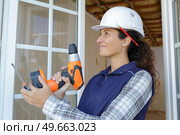 young happy woman in uniforl makes renovations with drill. Стоковое фото, агентство Ingram Publishing / Фотобанк Лори