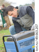 Builder turning on a mobile generator. Стоковое фото, агентство Ingram Publishing / Фотобанк Лори