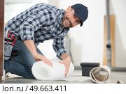 male handyman rolling carpet on floor at home. Стоковое фото, агентство Ingram Publishing / Фотобанк Лори