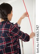 woman in a plaid-shirt lining the walls in her apartment. Стоковое фото, агентство Ingram Publishing / Фотобанк Лори