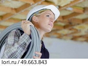female builder carrying cable on her shoulder. Стоковое фото, агентство Ingram Publishing / Фотобанк Лори