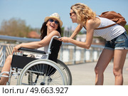 wheelchair bound blonde smiling with her friend. Стоковое фото, агентство Ingram Publishing / Фотобанк Лори