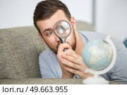 man considering a world globe with a magnifying glass. Стоковое фото, агентство Ingram Publishing / Фотобанк Лори