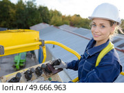 woman maneuvering cherry picker above warehouses. Стоковое фото, агентство Ingram Publishing / Фотобанк Лори