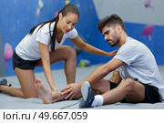 woman assisting climber with injury in the ankle. Стоковое фото, агентство Ingram Publishing / Фотобанк Лори