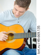 young man playing guitar and composing a song. Стоковое фото, агентство Ingram Publishing / Фотобанк Лори