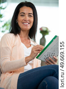 thoughtful attractive woman answering crossword puzzle. Стоковое фото, агентство Ingram Publishing / Фотобанк Лори