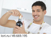 man in apron opening bottle of wine. Стоковое фото, агентство Ingram Publishing / Фотобанк Лори
