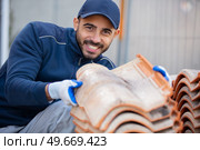 young happy man tiling on balcony ceramic tiles. Стоковое фото, агентство Ingram Publishing / Фотобанк Лори
