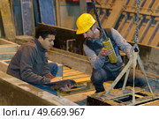 men using hoist in industrial building. Стоковое фото, агентство Ingram Publishing / Фотобанк Лори
