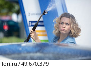 unsure woman standing with spray foam to clean car. Стоковое фото, агентство Ingram Publishing / Фотобанк Лори