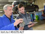 student with instructor repairing a car during apprenticeship. Стоковое фото, агентство Ingram Publishing / Фотобанк Лори
