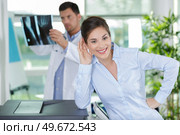 doctor holding x-ray imaging while patient is looking at camera. Стоковое фото, агентство Ingram Publishing / Фотобанк Лори