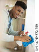 man cleaning window with rag and spray cleaner at home. Стоковое фото, агентство Ingram Publishing / Фотобанк Лори