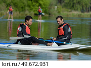 friends chating on stand up paddleboarding. Редакционное фото, агентство Ingram Publishing / Фотобанк Лори