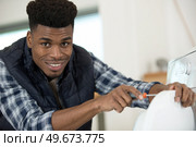 happy electrical worker is screwing a washing machine. Стоковое фото, агентство Ingram Publishing / Фотобанк Лори