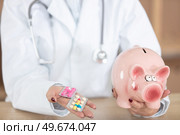 doctor holding piggybank and blisters of tablets. Стоковое фото, агентство Ingram Publishing / Фотобанк Лори