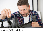 man repairing a chair with an allen key. Стоковое фото, агентство Ingram Publishing / Фотобанк Лори