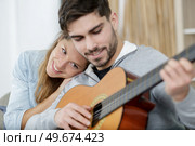 woman cuddling into her boyfriend as he plays the guitar. Стоковое фото, агентство Ingram Publishing / Фотобанк Лори