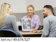 gynecologist showing scan of unborn baby to happy couple. Стоковое фото, агентство Ingram Publishing / Фотобанк Лори