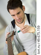 man using a screw driver on guitar. Стоковое фото, агентство Ingram Publishing / Фотобанк Лори