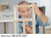 senior man using screwdriver to assemble cupboard component. Стоковое фото, агентство Ingram Publishing / Фотобанк Лори