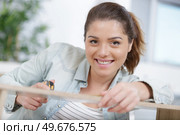 happy woman measure wood plank before saw. Стоковое фото, агентство Ingram Publishing / Фотобанк Лори