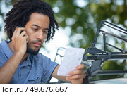 man reading instructions for securing a vehicle roof rack. Стоковое фото, агентство Ingram Publishing / Фотобанк Лори