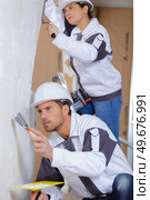 male and female plasterer in uniform polishing the wall. Стоковое фото, агентство Ingram Publishing / Фотобанк Лори