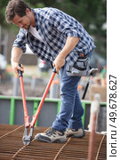 male builder using bolt croppers on concrete reinforcement bars. Стоковое фото, агентство Ingram Publishing / Фотобанк Лори