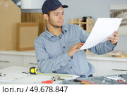 young man following instructions to assemble kitchen furniture. Стоковое фото, агентство Ingram Publishing / Фотобанк Лори