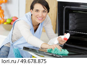 beautiful woman cleaning oven with spray bottle and rag. Стоковое фото, агентство Ingram Publishing / Фотобанк Лори