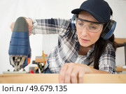 a woman is cutting wood. Стоковое фото, агентство Ingram Publishing / Фотобанк Лори