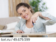 happy woman moving in assembly furniture at new home. Стоковое фото, агентство Ingram Publishing / Фотобанк Лори