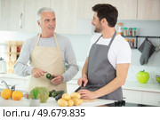 senior man with beard preparing dinner with son. Стоковое фото, агентство Ingram Publishing / Фотобанк Лори