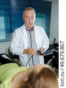 senior doctor taking womans blood pressure at home. Стоковое фото, агентство Ingram Publishing / Фотобанк Лори